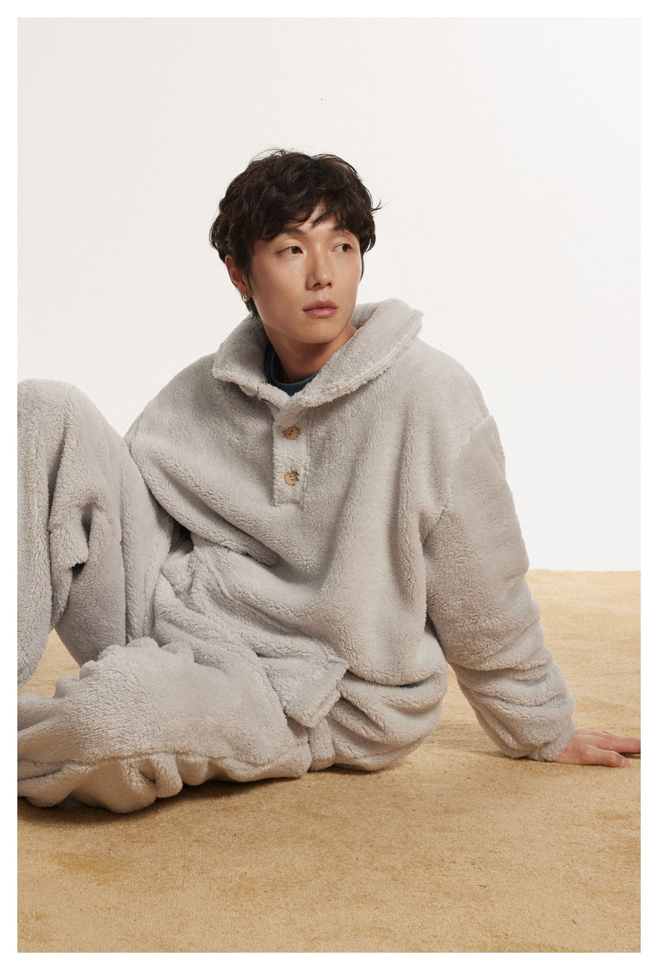Seated model wearing a light gray plush pullover with two buttons and matching pants.