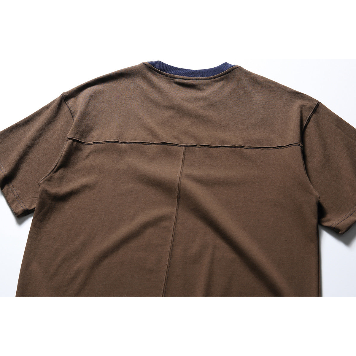 Back view of a brown short-sleeve T-shirt with a navy collar, horizontal upper-back seam, and vertical center seam.