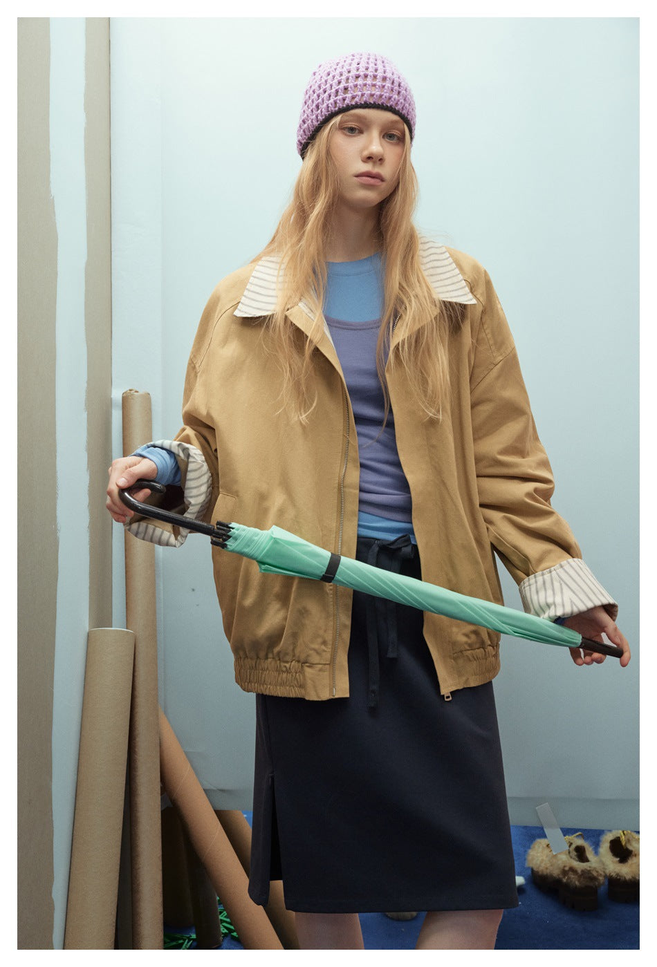 Front view of a model in a tan jacket with a striped collar, cuffs, and gathered hem.