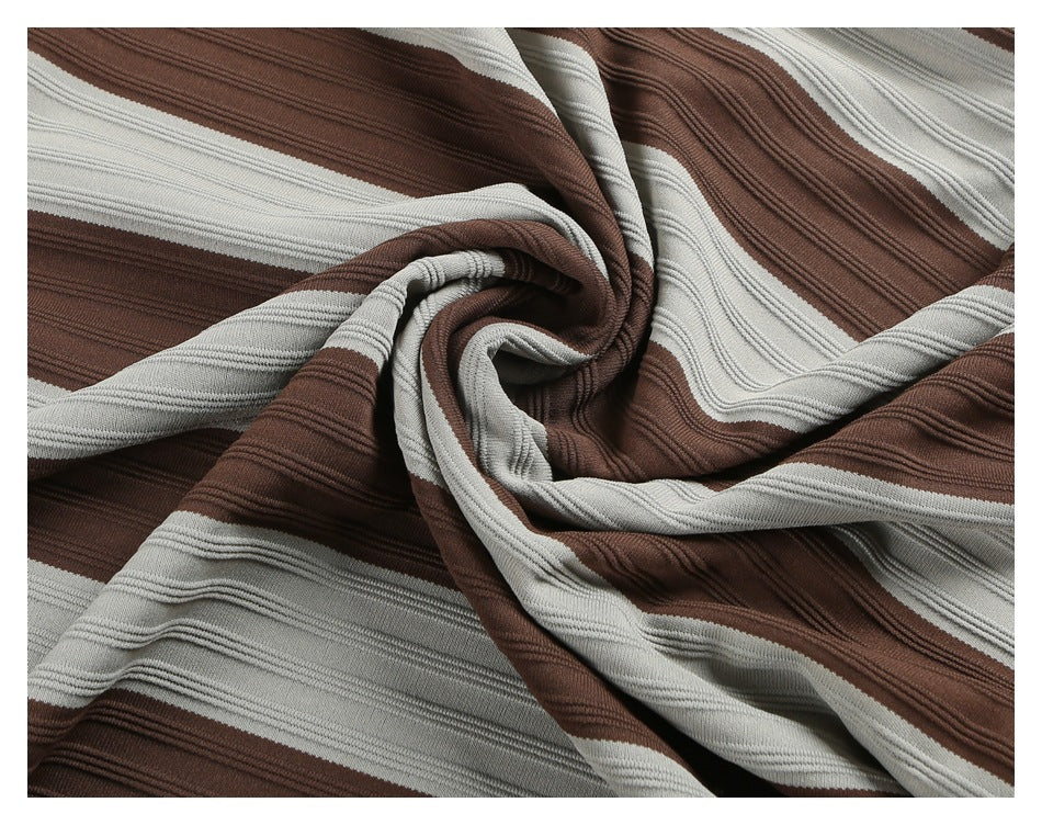 Close-up of brown and light gray fabric with broad stripes and raised ribbed texture, gathered into folds.