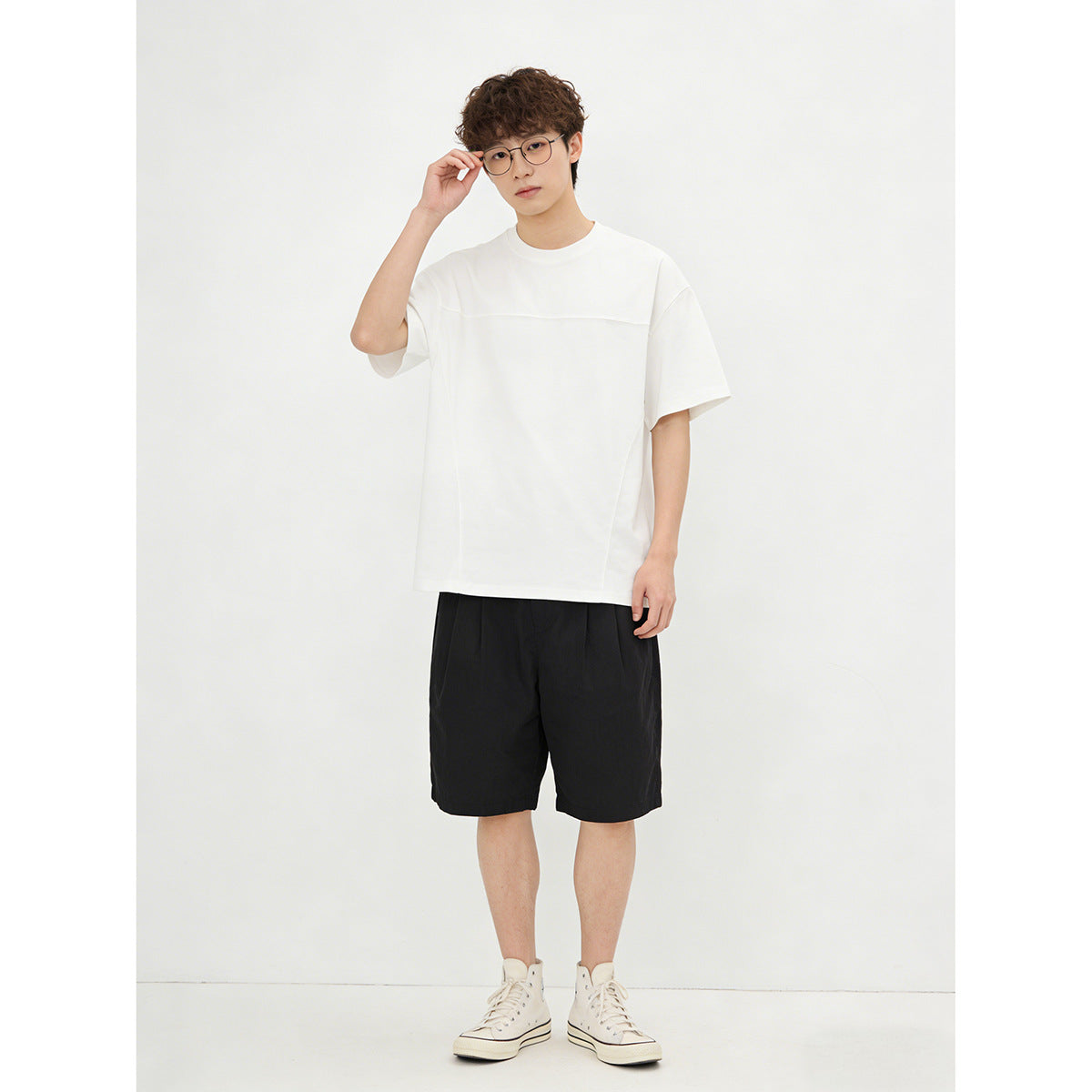 Model wearing an oversized white short-sleeve crewneck T-shirt with a horizontal chest seam.