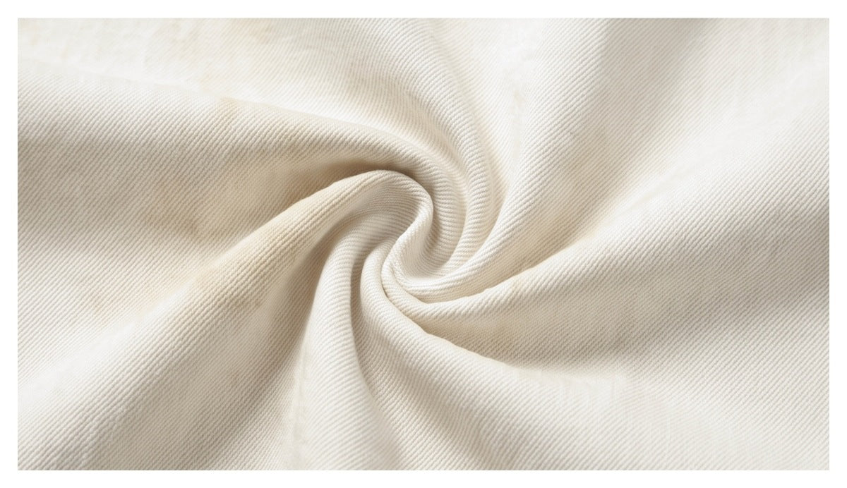 Close-up of off-white fabric twisted into folds, showing its fine diagonal weave.