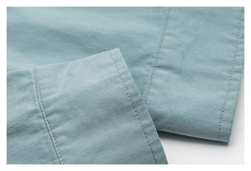 Close-up of pale blue shirt fabric and stitched panel seams.
