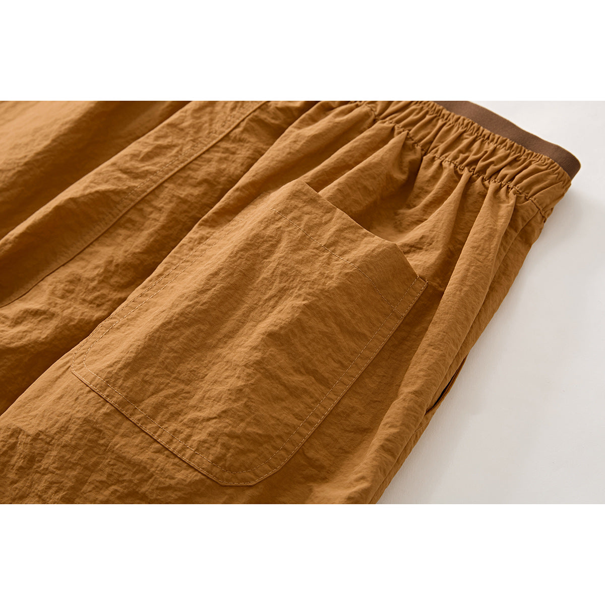 Close-up of ochre shorts showing a large patch pocket, elastic waistband, and side seam.