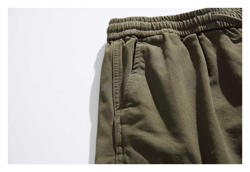 Close-up of olive shorts showing the elastic waistband and side pocket opening.