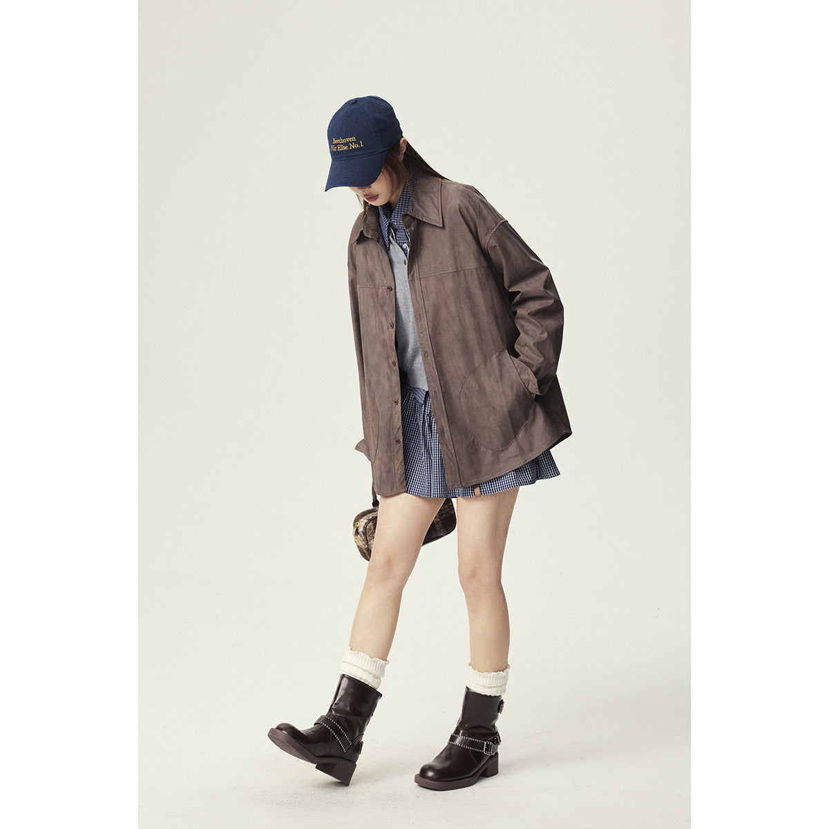 Model wearing an oversized brown button-front jacket with large patch pockets over a checked outfit.