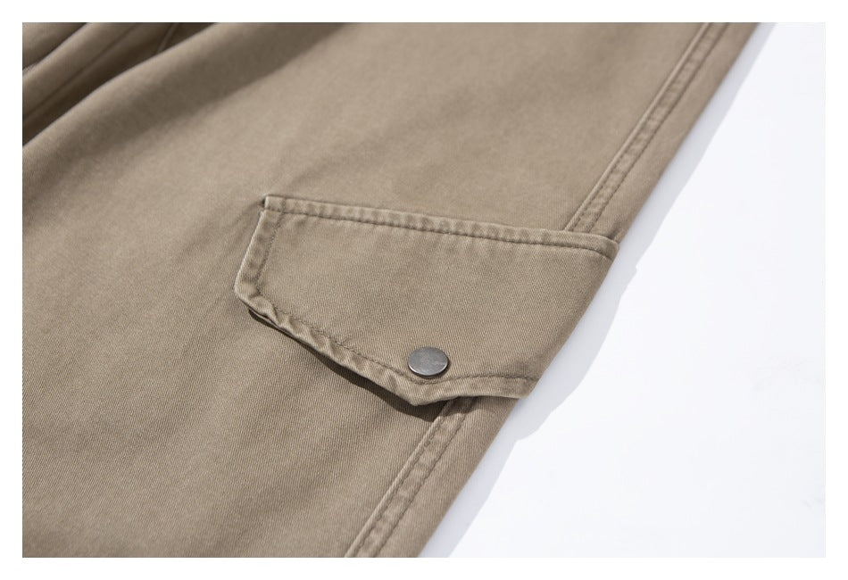 Close-up of a taupe pants leg with a buttoned flap pocket.