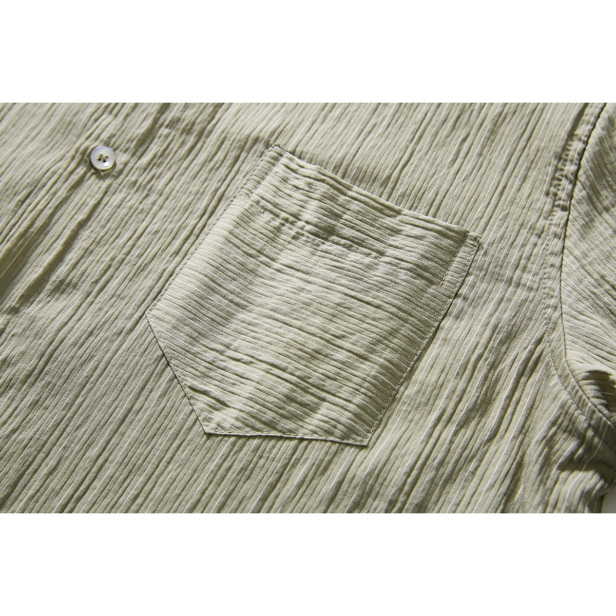 Close-up of the olive-gray shirt’s chest pocket, button, and textured striped fabric.