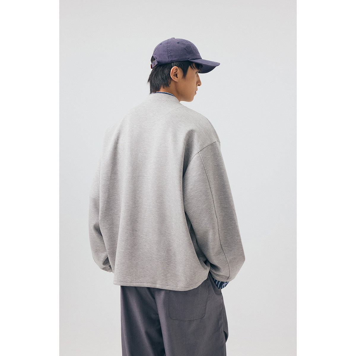 Rear view of a model wearing the light gray jacket and loose charcoal trousers.