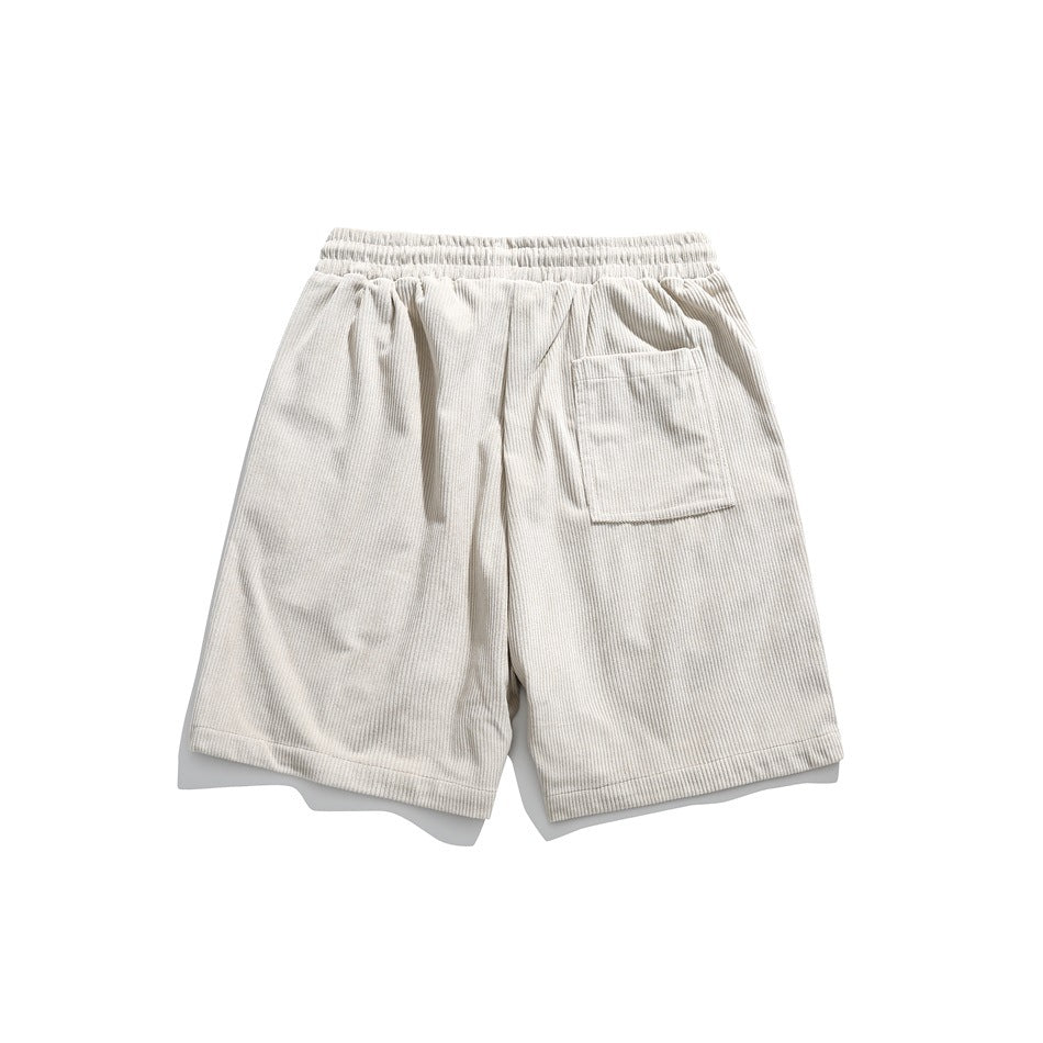 Back view of beige corduroy-style shorts with elastic waistband and a patch pocket on the right side, flat lay