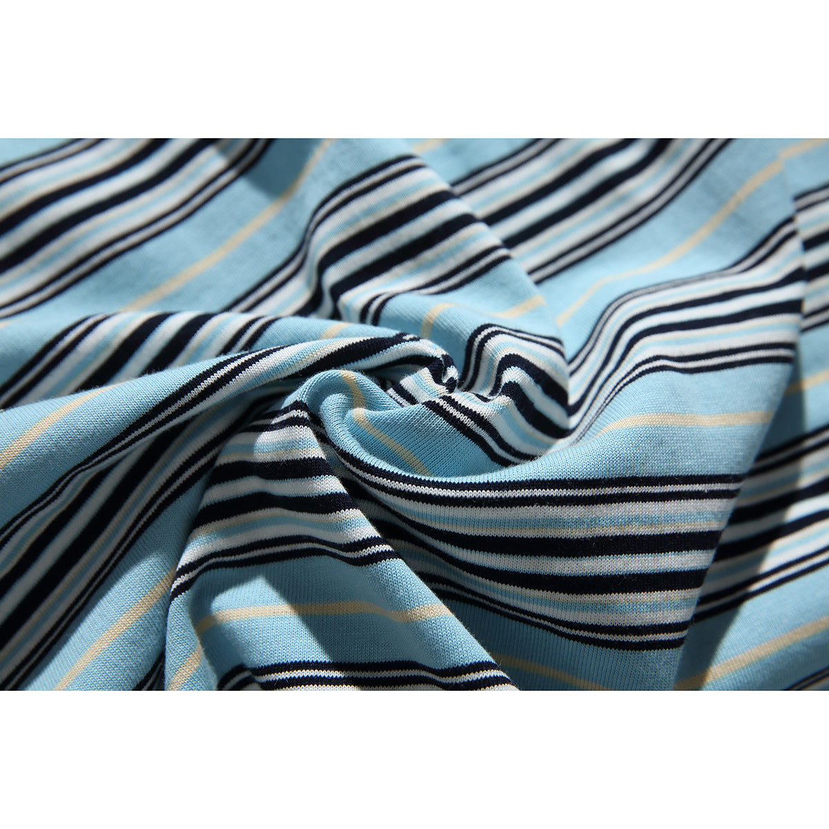 Macro view of the blue, black, white, and tan striped fabric in soft folds.