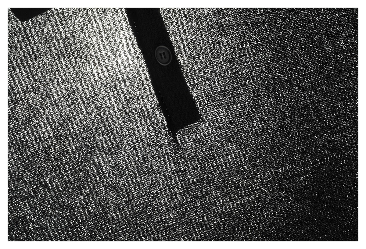 Close-up of a black-and-white speckled knit garment with a black button placket and button.