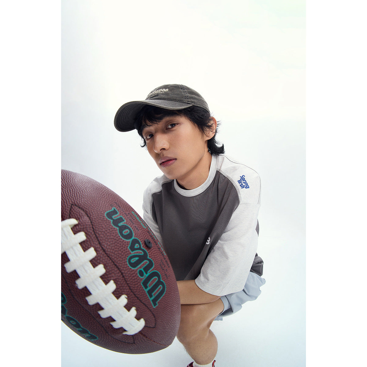 Close-up of a model wearing a charcoal T-shirt with light gray raglan sleeves and a small chest logo.