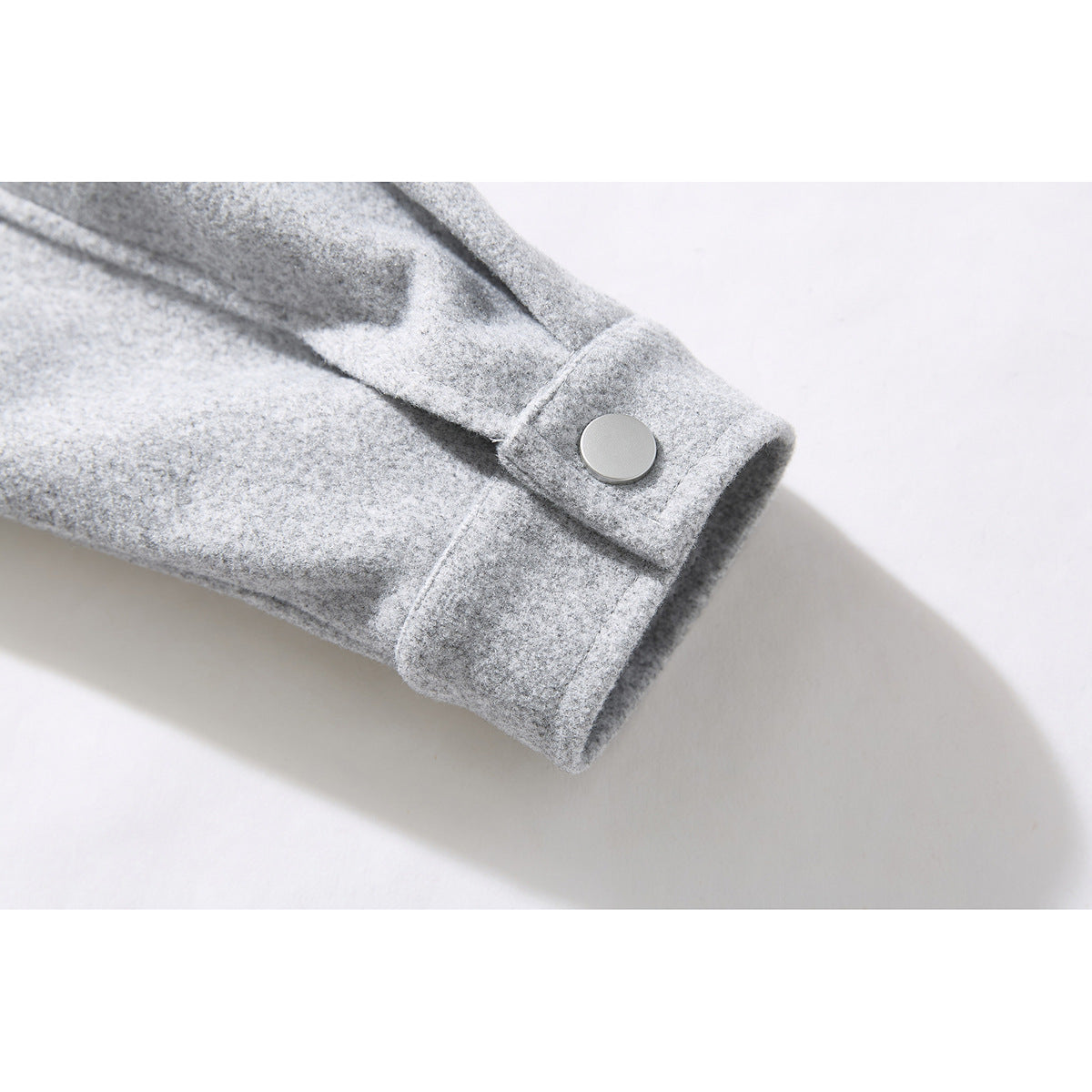 Close-up of a light gray jacket sleeve cuff with a round snap button.