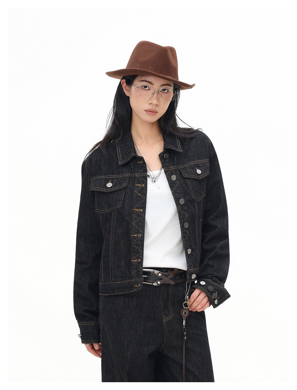 Model wearing a dark indigo denim jacket with contrast stitching and flap pockets, styled with a white top and wide-leg