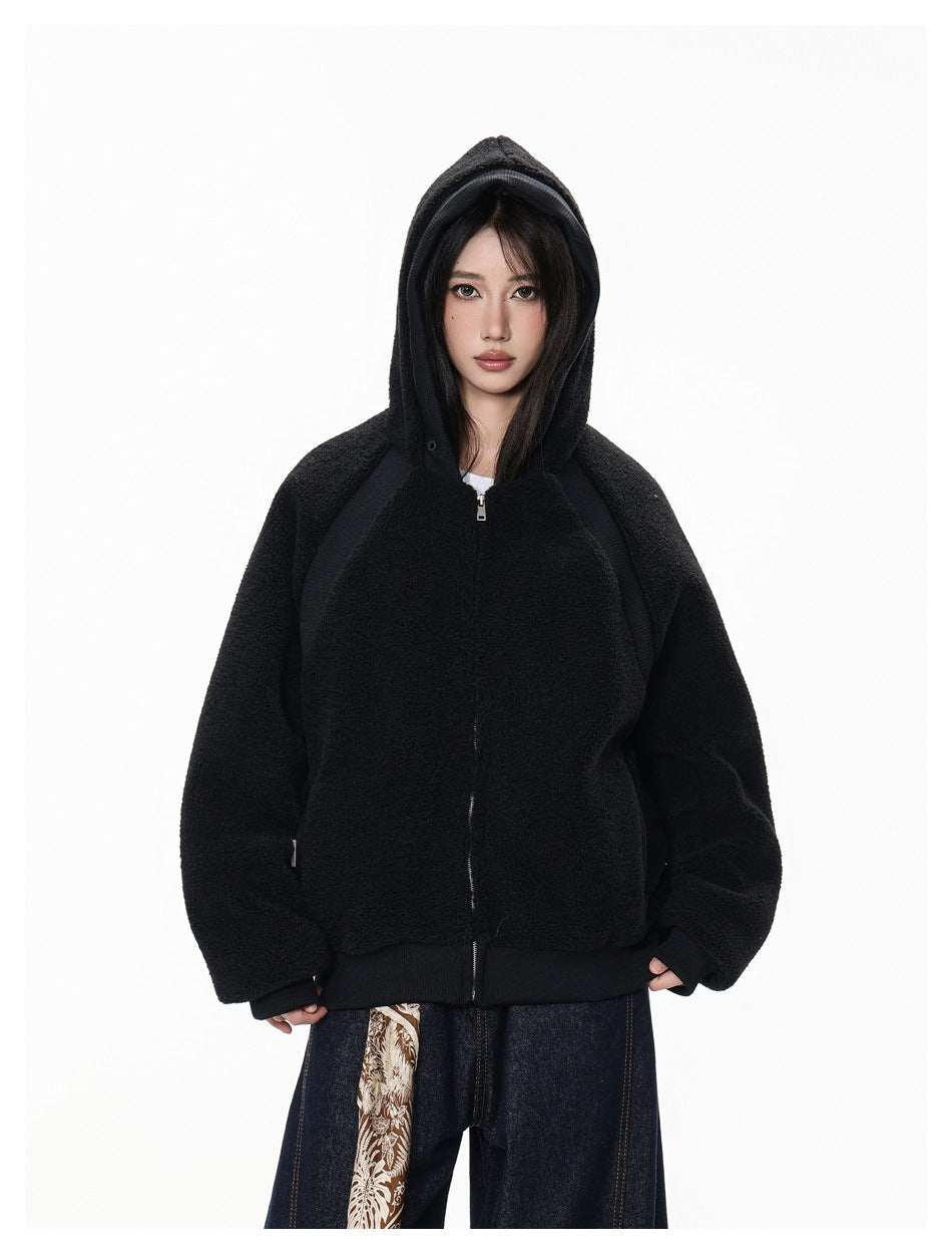 Model wearing a black plush zip-up hoodie with the hood raised, shown from the front.