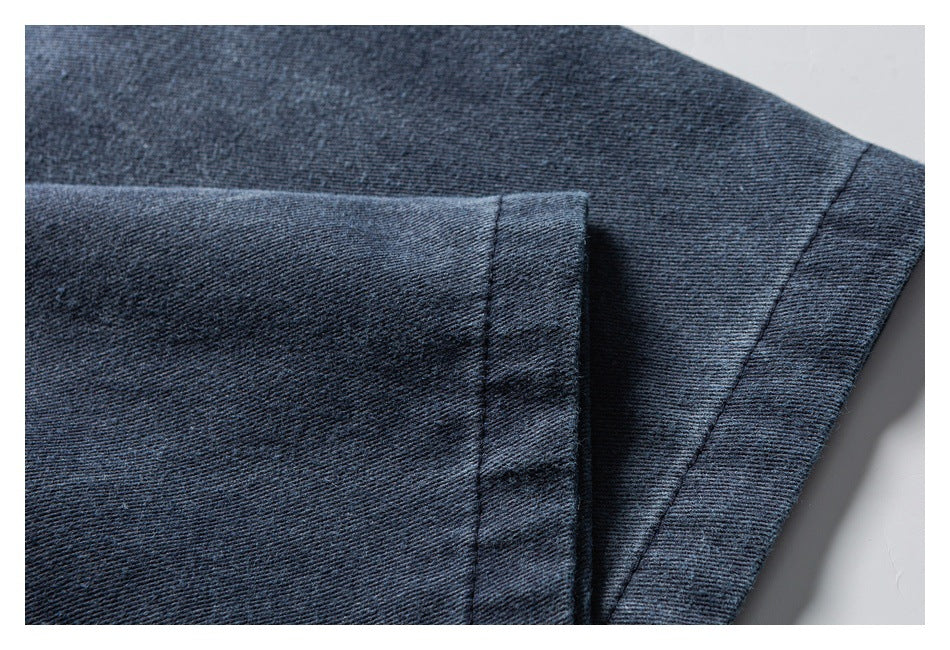Close-up of dark blue denim showing a folded edge and parallel stitched seams.