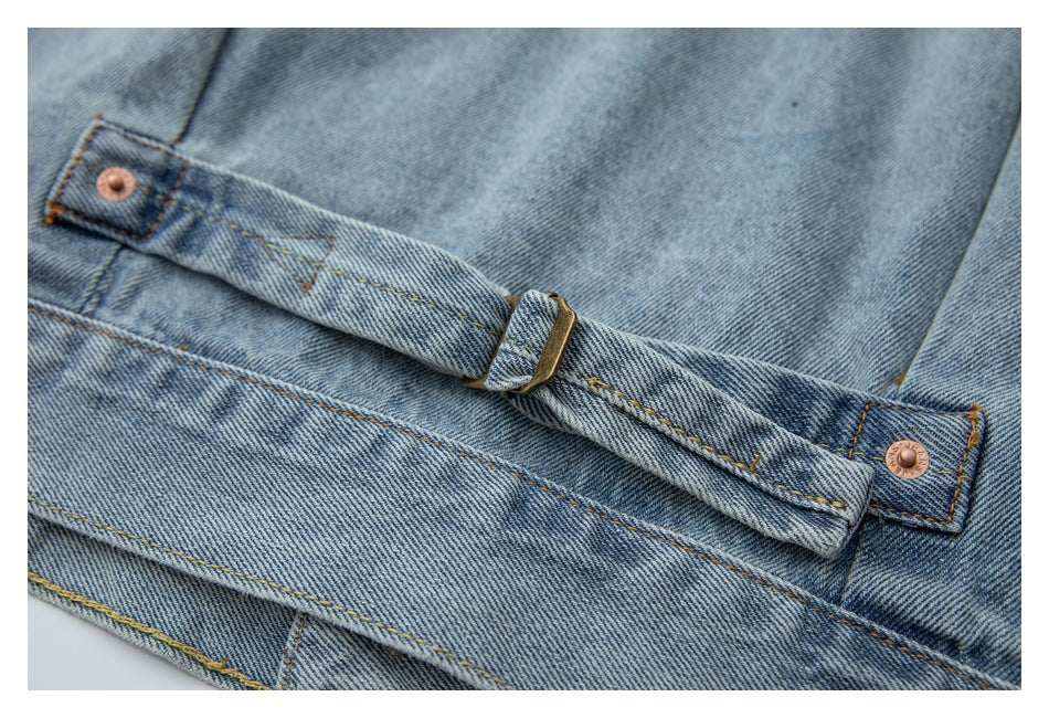 Close-up of a light blue denim jacket's adjustable waist strap, metal buckle, and copper rivets.