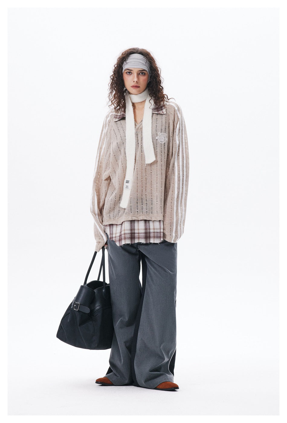 Full-length model wearing a beige open-knit striped pullover with plaid collar, white scarf, gray headband, and wide-leg gray