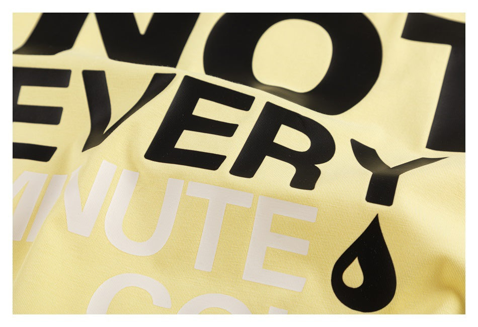Close-up of the pale yellow T-shirt’s black and white lettering and black droplet graphic.