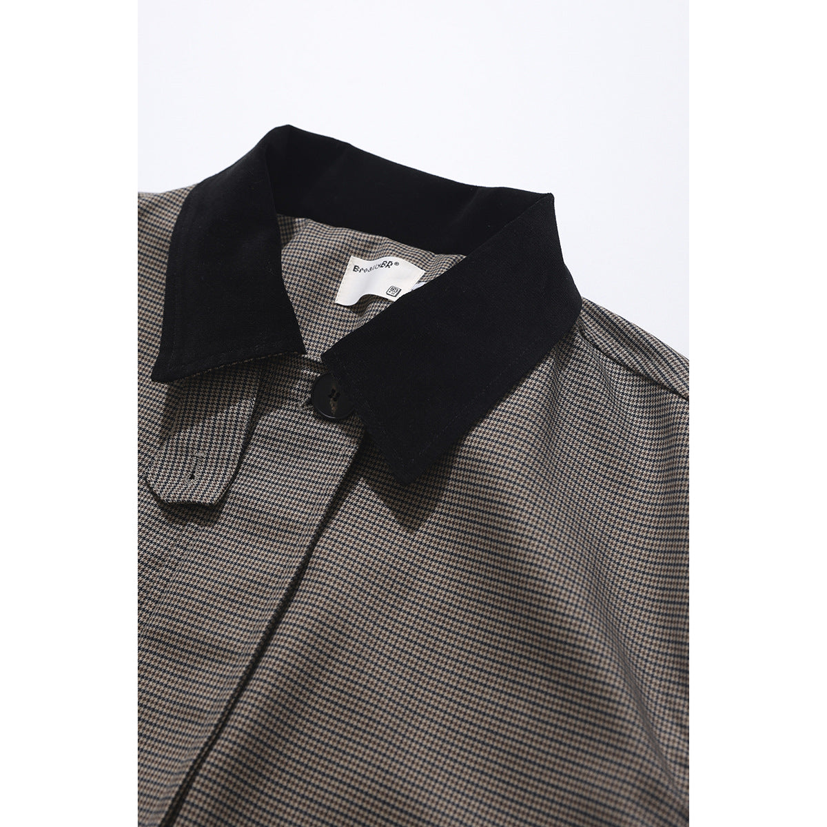 Close-up of a brown and black houndstooth jacket with a wide black collar and front button.