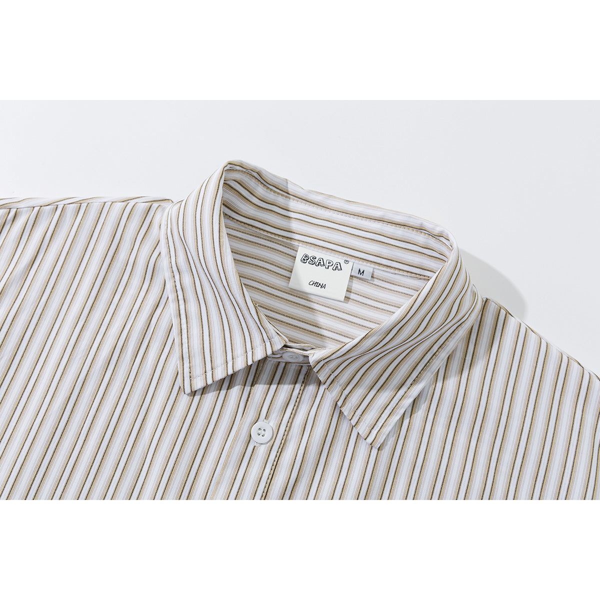 Close-up of a white shirt collar and label, showing fine gray and tan stripes and a button.