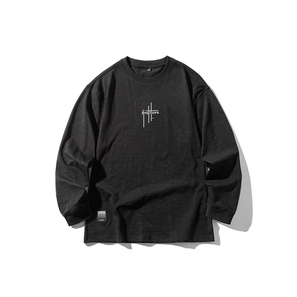 Black long-sleeve crew-neck top flat lay with small chest lettering graphic and hem label