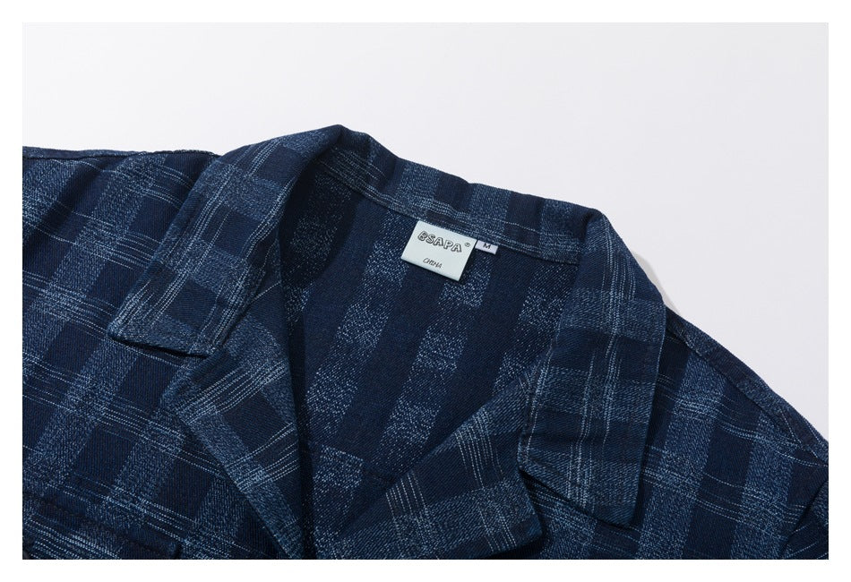Close-up of the collar and lapels of a navy plaid shirt, with a neck label visible.