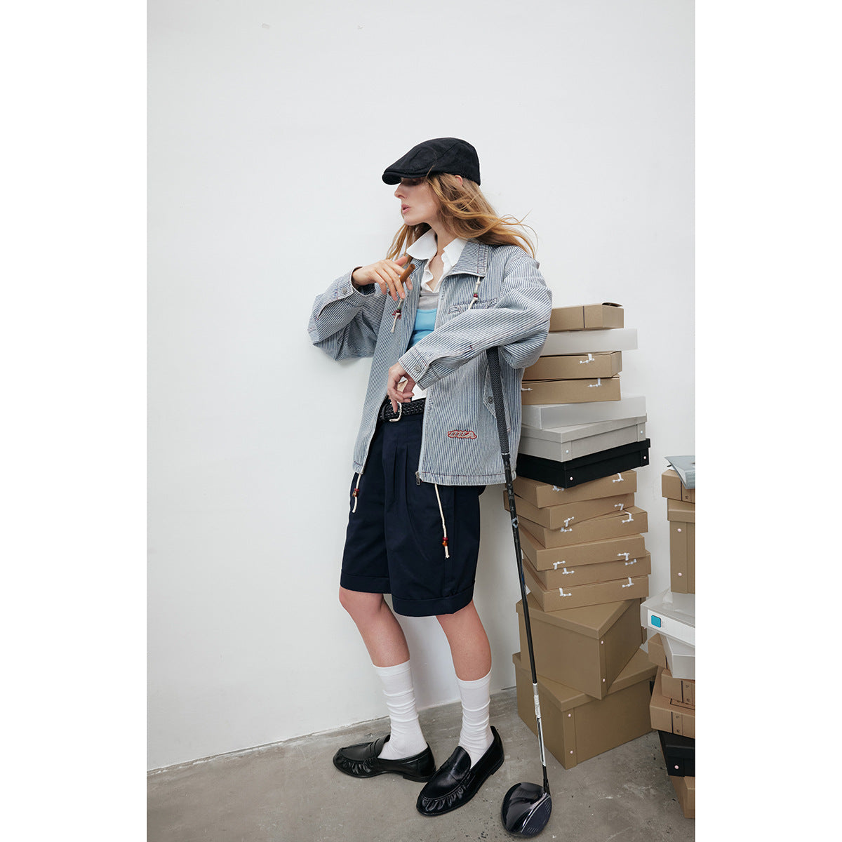 Model wears a blue-and-white pinstriped jacket with navy shorts, white socks, and black loafers.