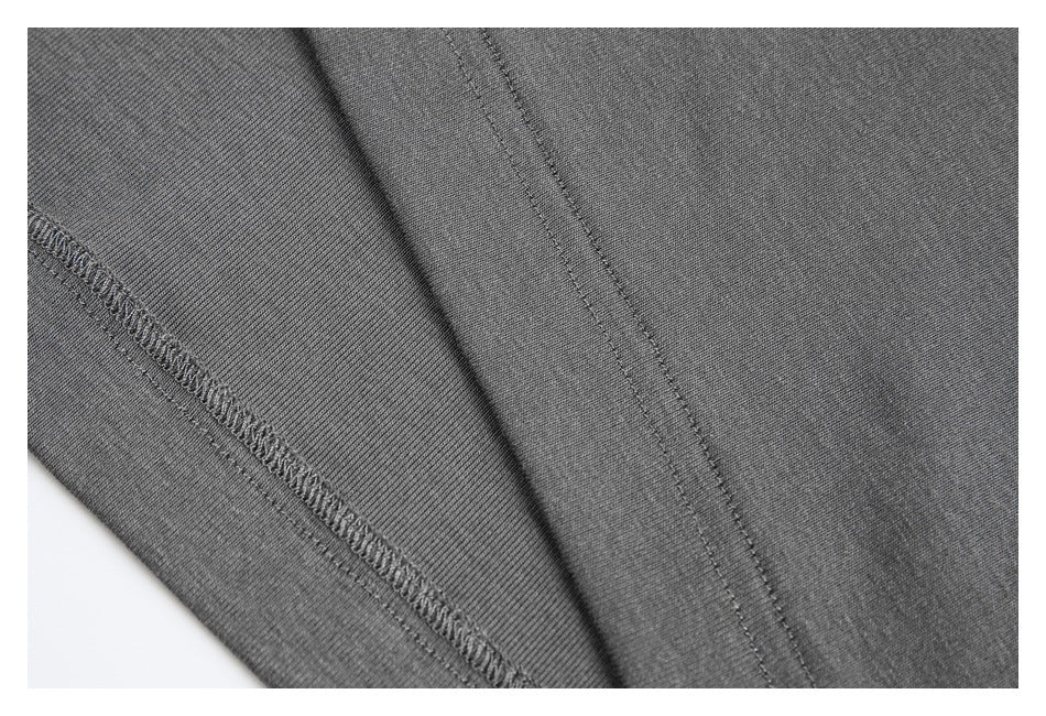 Close-up of gray garment fabric showing a folded edge and stitched seams.