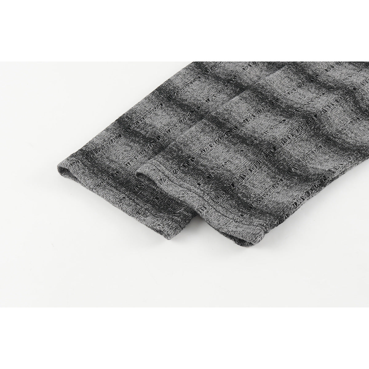 Close-up of the hem and stitching on a gray-and-black patterned long-sleeve shirt.