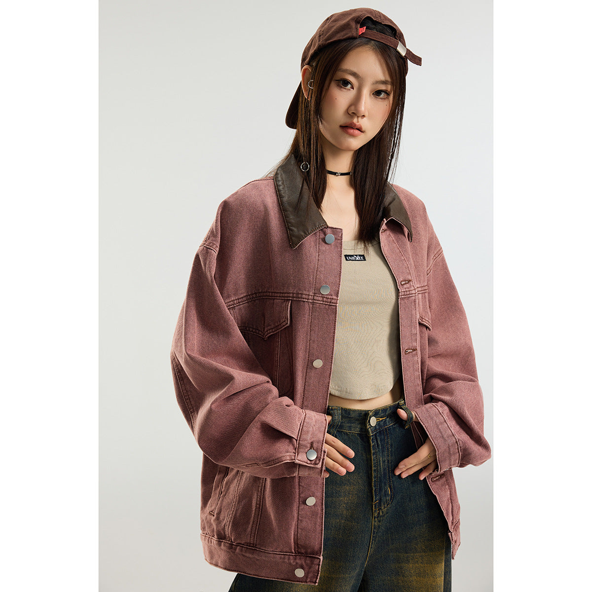 A model wears an oversized dusty rose jacket with a dark brown collar, snap buttons, and flap chest pockets.