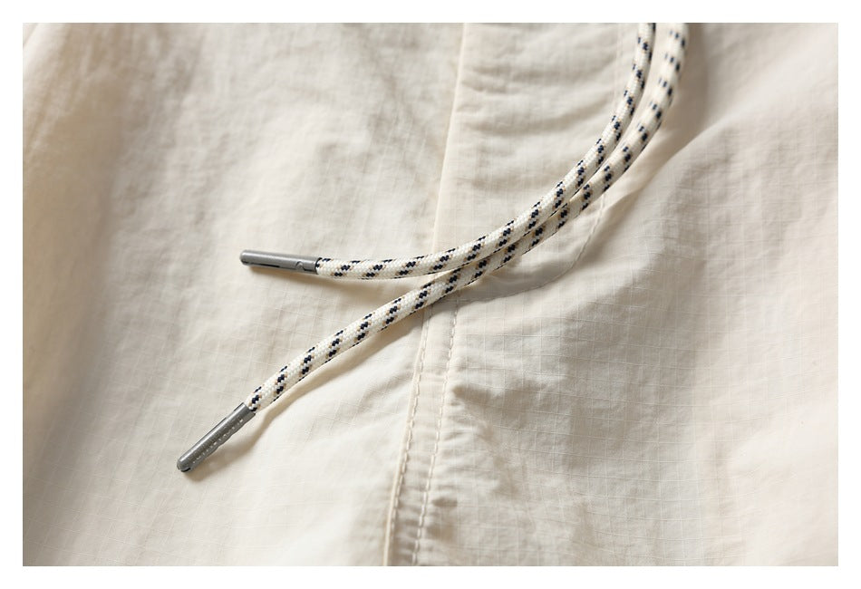 Close-up of the ivory shorts' black-speckled drawstrings with metal tips against the front panel.