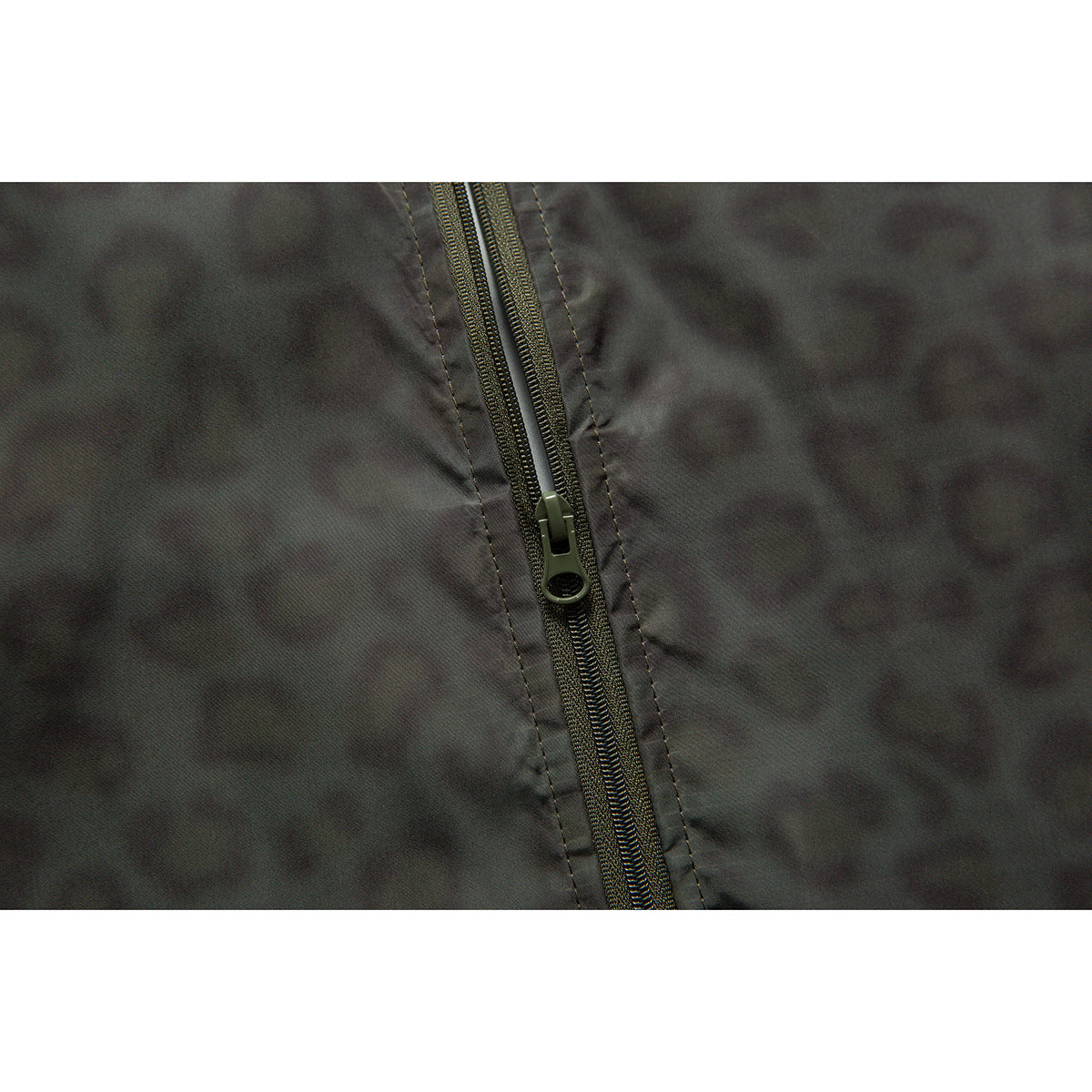 Close-up of the dark jacket's front zipper and stitching against its subtle patterned fabric.