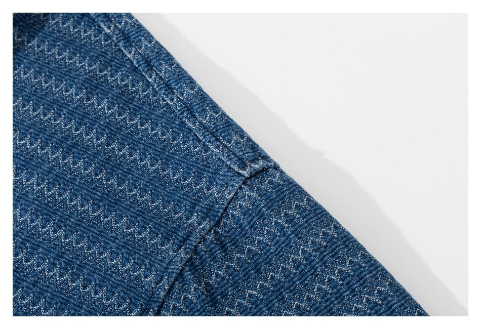 Close-up of a shoulder seam on blue zigzag-patterned shirt fabric.