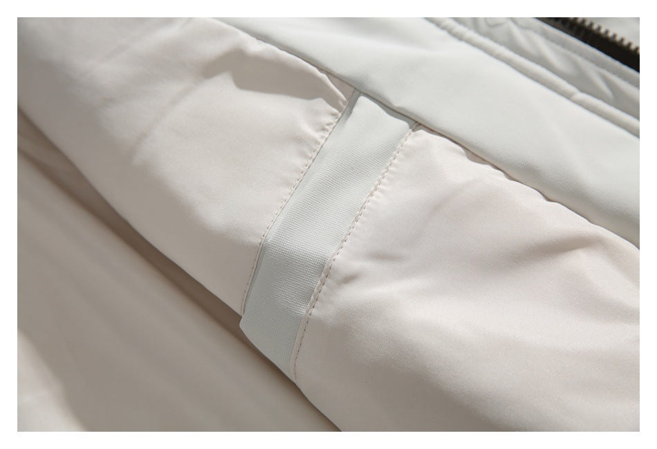 Close-up of a white jacket sleeve with a stitched fabric adjustment tab.