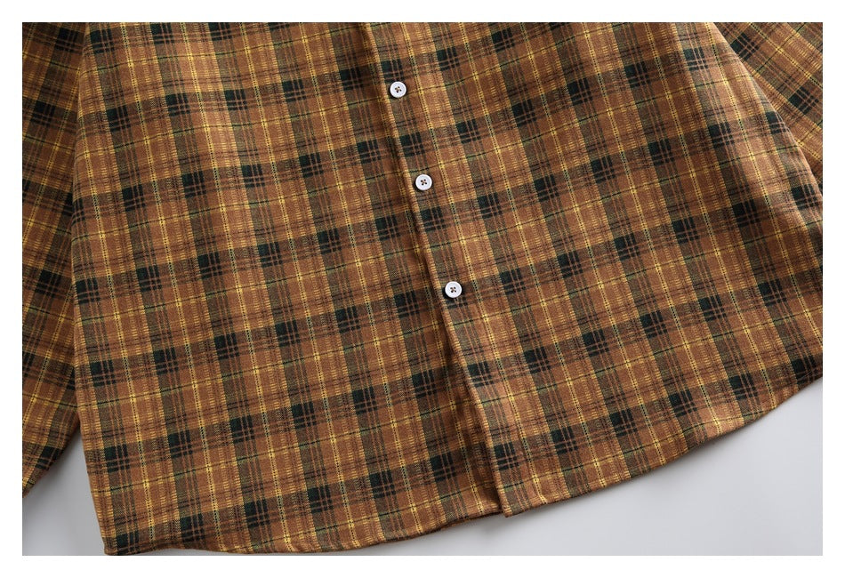 Close-up of the brown, mustard, and dark green plaid shirt front with three white buttons.