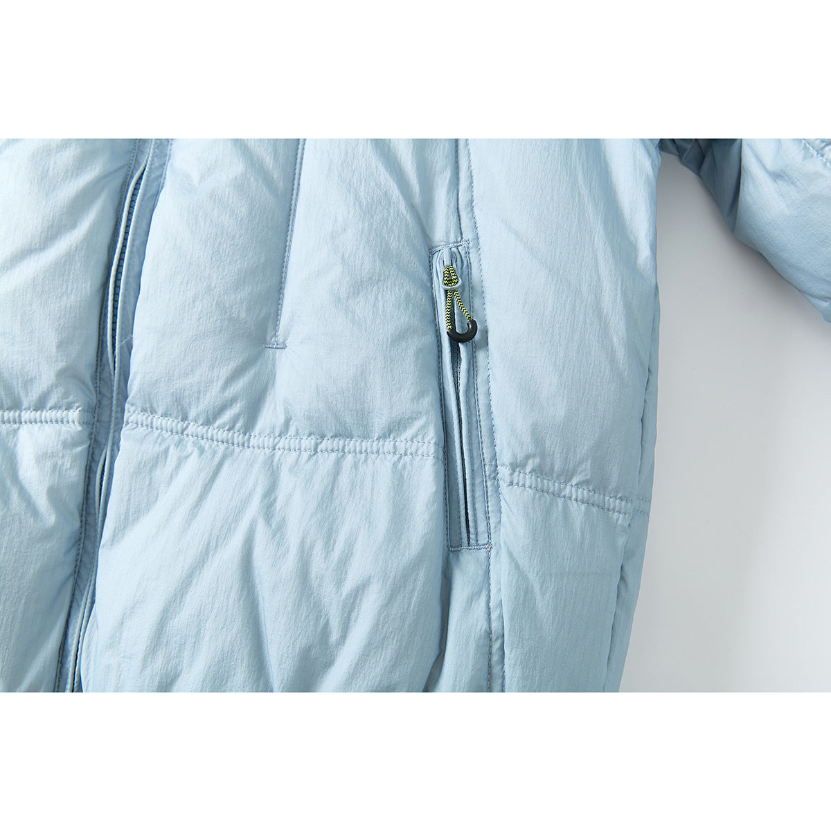 Close-up of a pale blue puffer jacket showing a vertical zip pocket with a black-and-yellow pull.