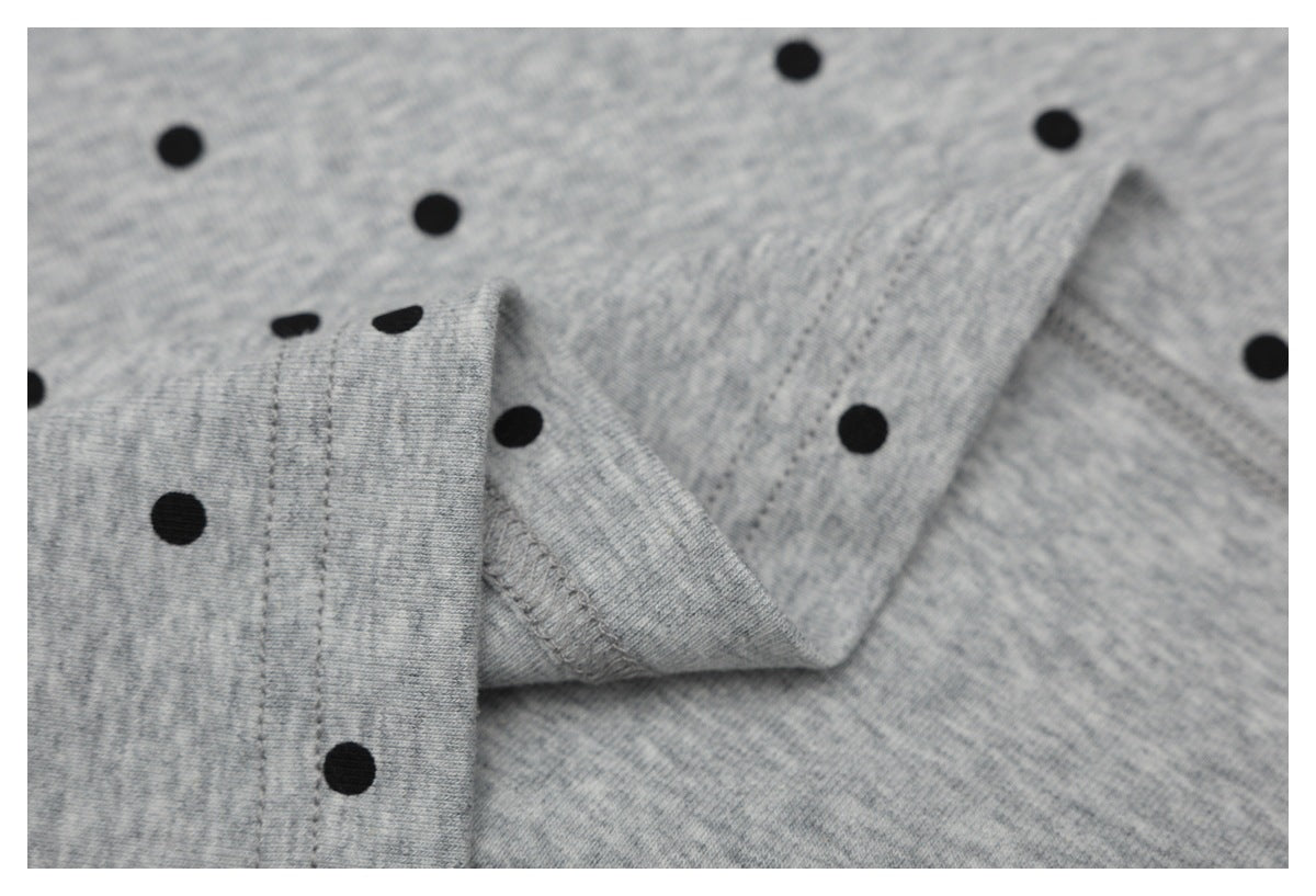 Close-up of a folded edge and stitching on the gray shirt with black dots.