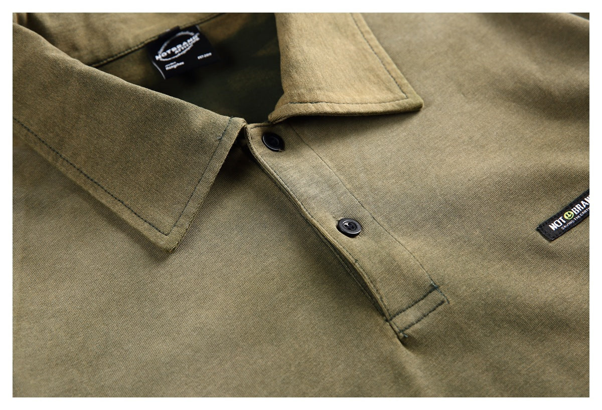 Close-up of an olive-green collared shirt showing the collar, black buttons, and a small sewn logo patch.