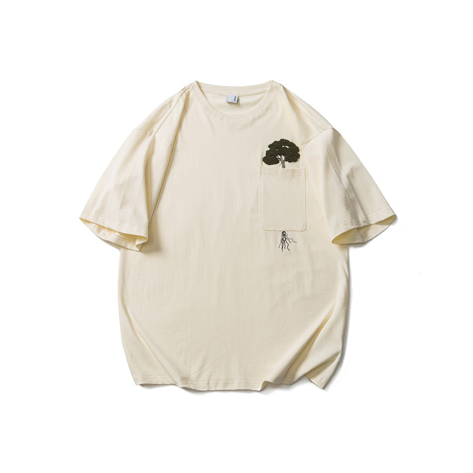Beige short-sleeve T-shirt with a chest pocket and a green embroidered tree growing out of it, flat lay