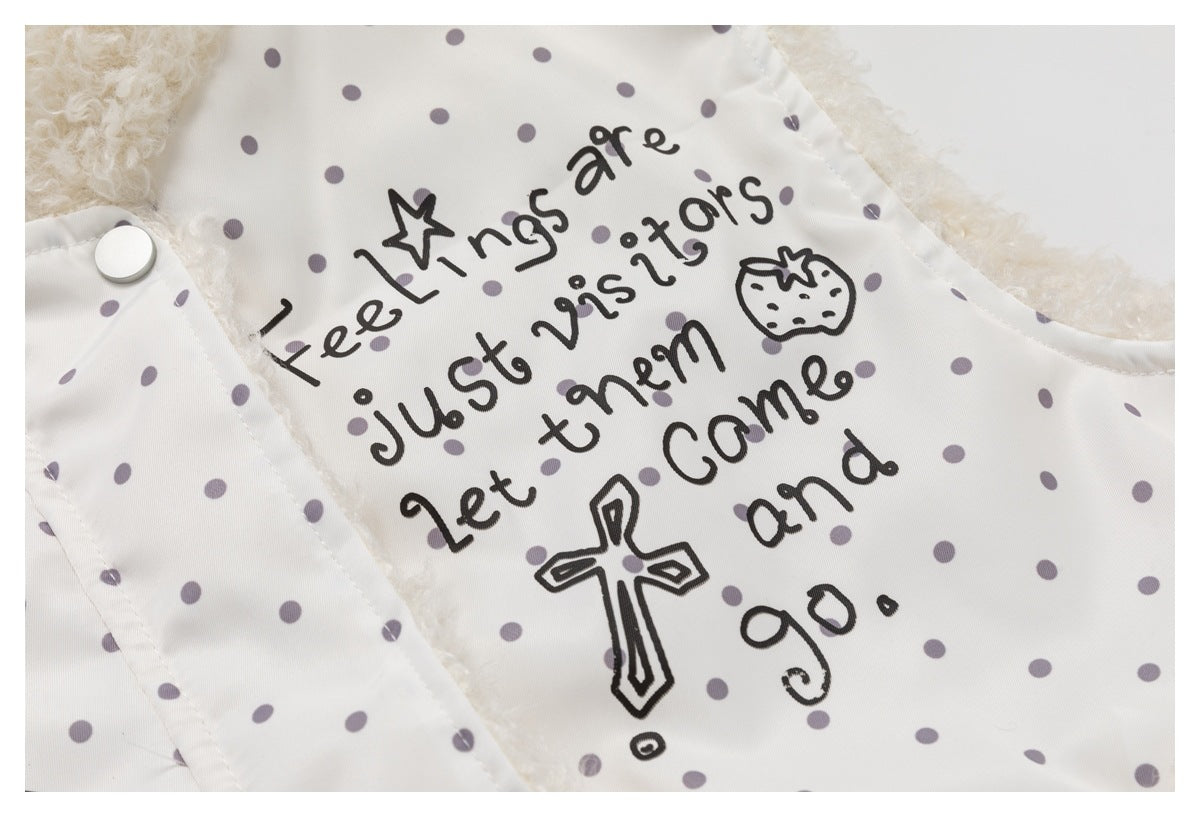 Close-up of black handwritten English text and a cross on an ivory jacket with gray polka dots.