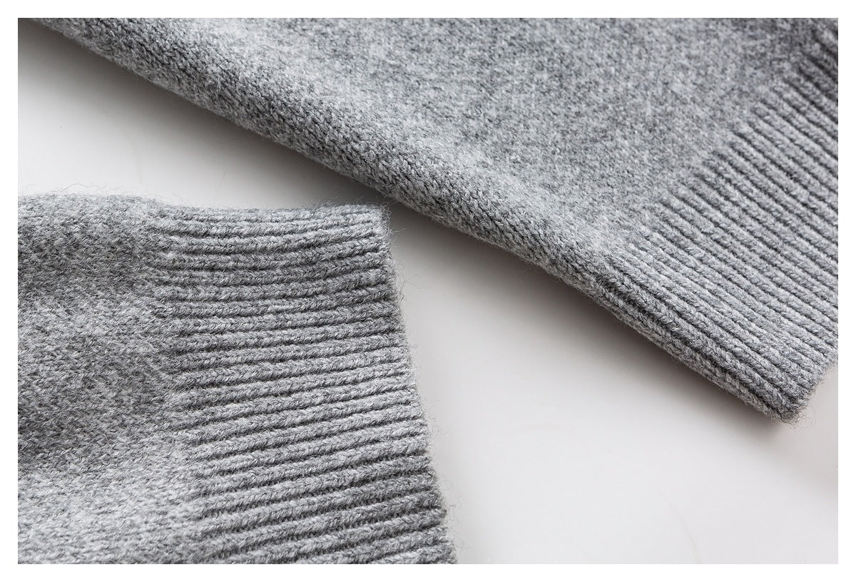Close-up of gray sweater sleeves with ribbed cuffs and a fine knit texture.