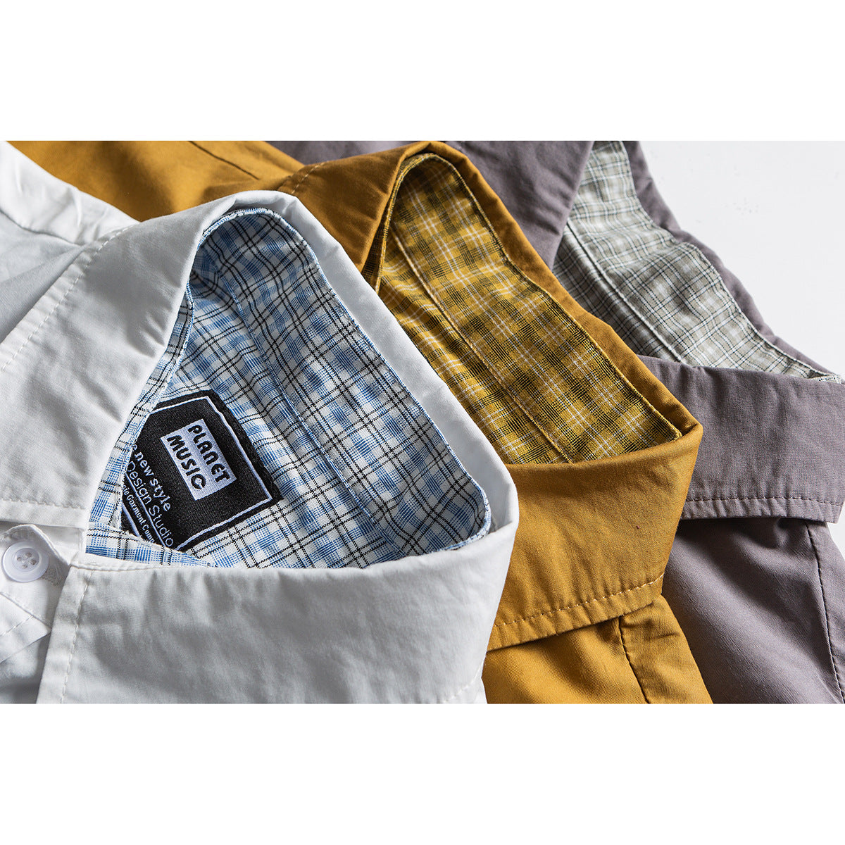 Close-up of white, mustard, and mauve shirts showing blue, yellow, and gray plaid inner yokes and labels.