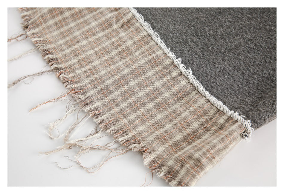 Close-up of dark gray fabric beside a beige striped, fringed textile edge.