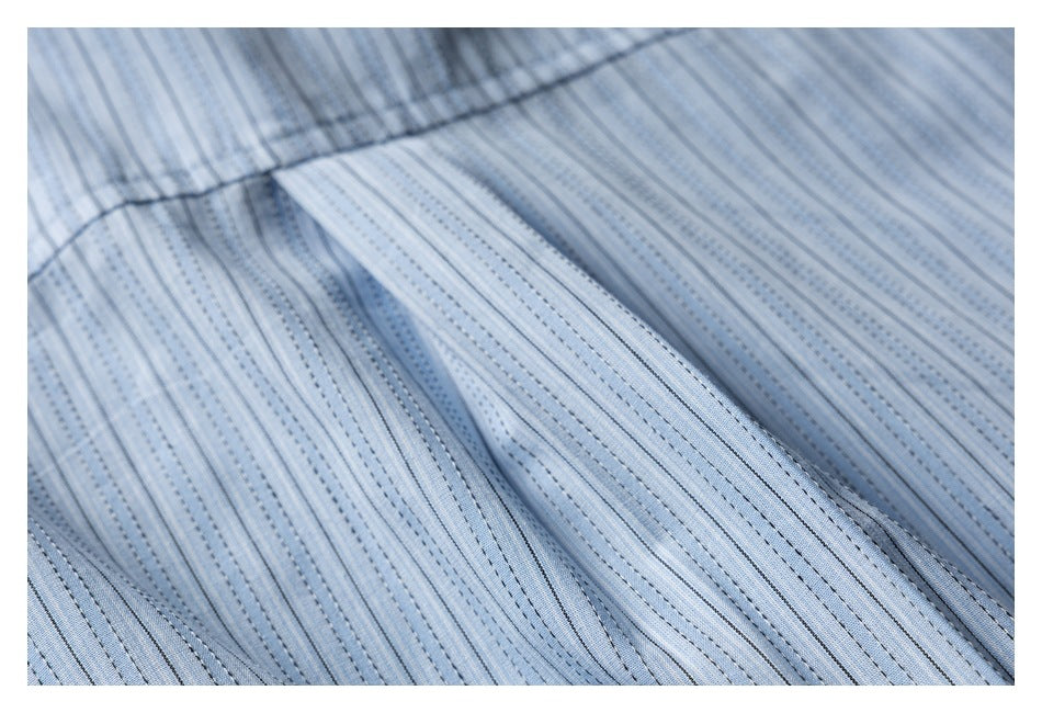 Close-up of light blue striped garment fabric with a stitched seam and folded edge.
