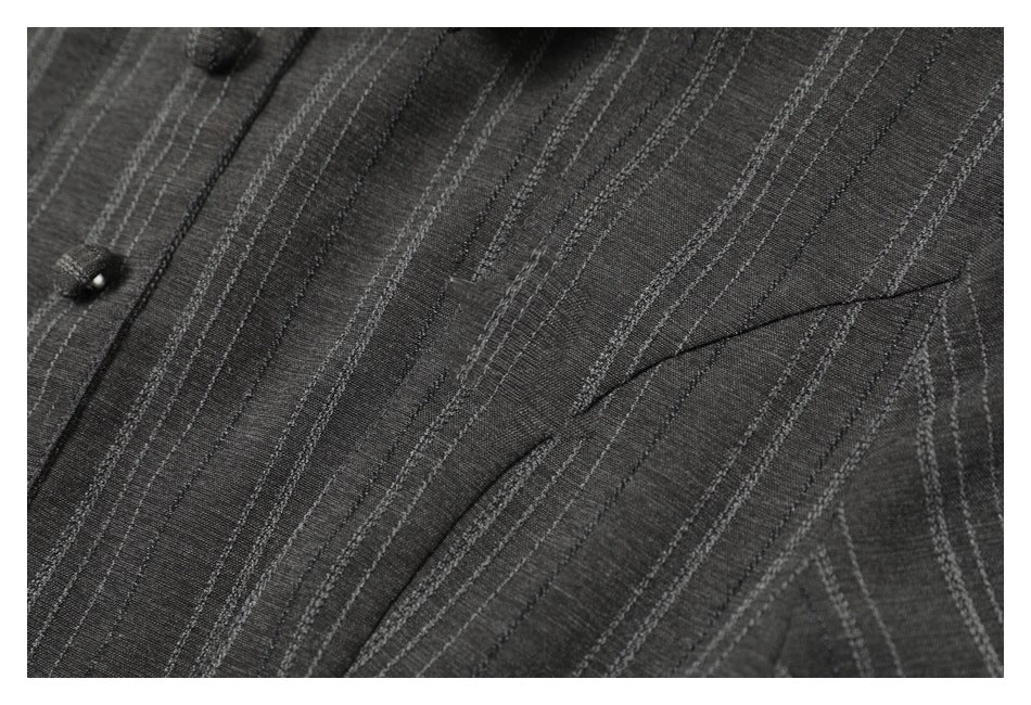 Close-up of a charcoal gray striped garment front with buttons and a diagonal welt pocket.
