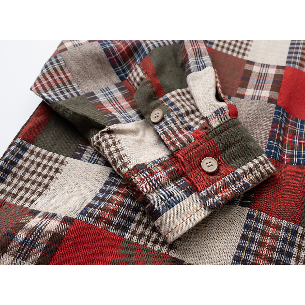 Close-up of a patchwork plaid shirt sleeve and buttoned cuff in red, cream, navy, and olive.
