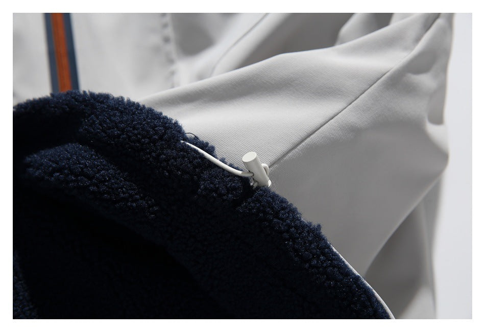 Close-up of a light gray shell joined to dark navy fleece, with a small white cord toggle.