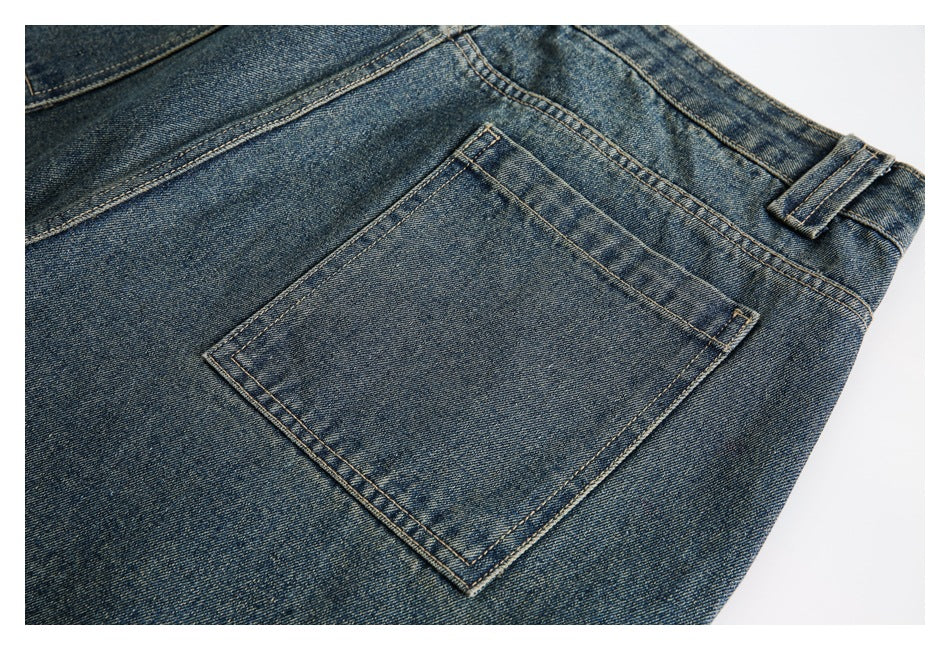 Close-up of a square back pocket and belt loop on blue faded jeans.